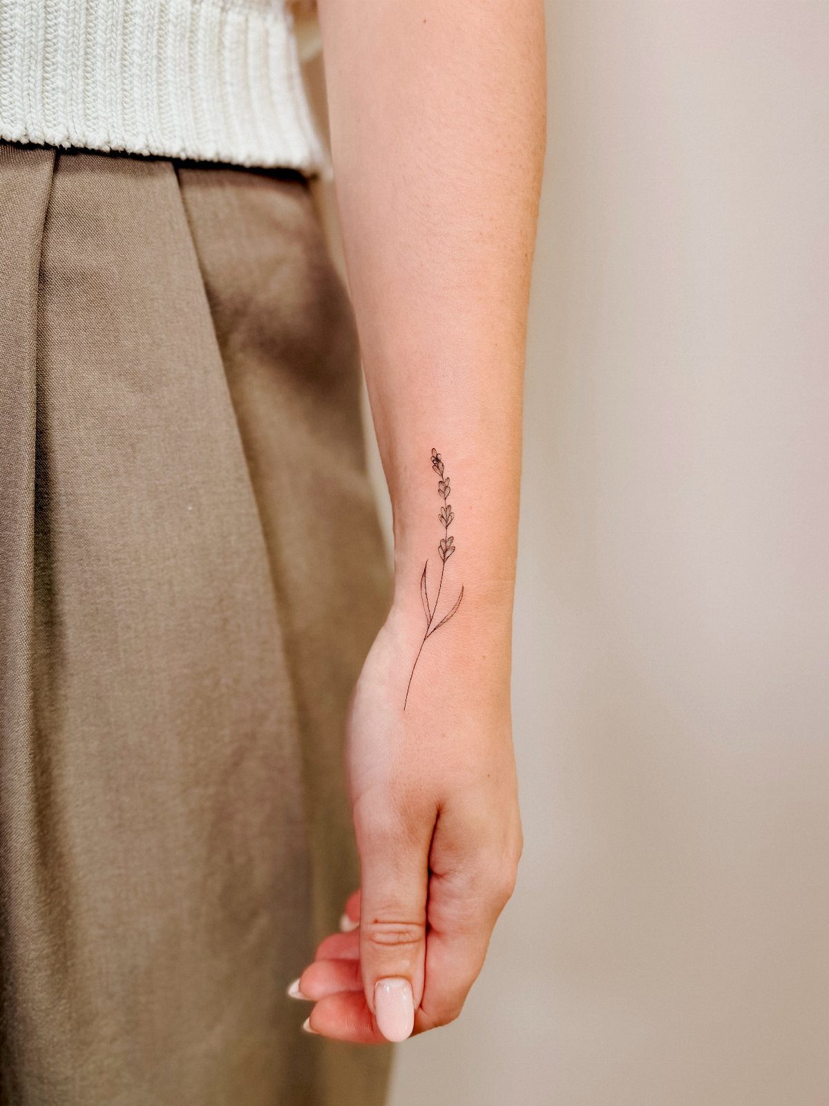 Fine line floral tattoo on the inner forearm of a person.