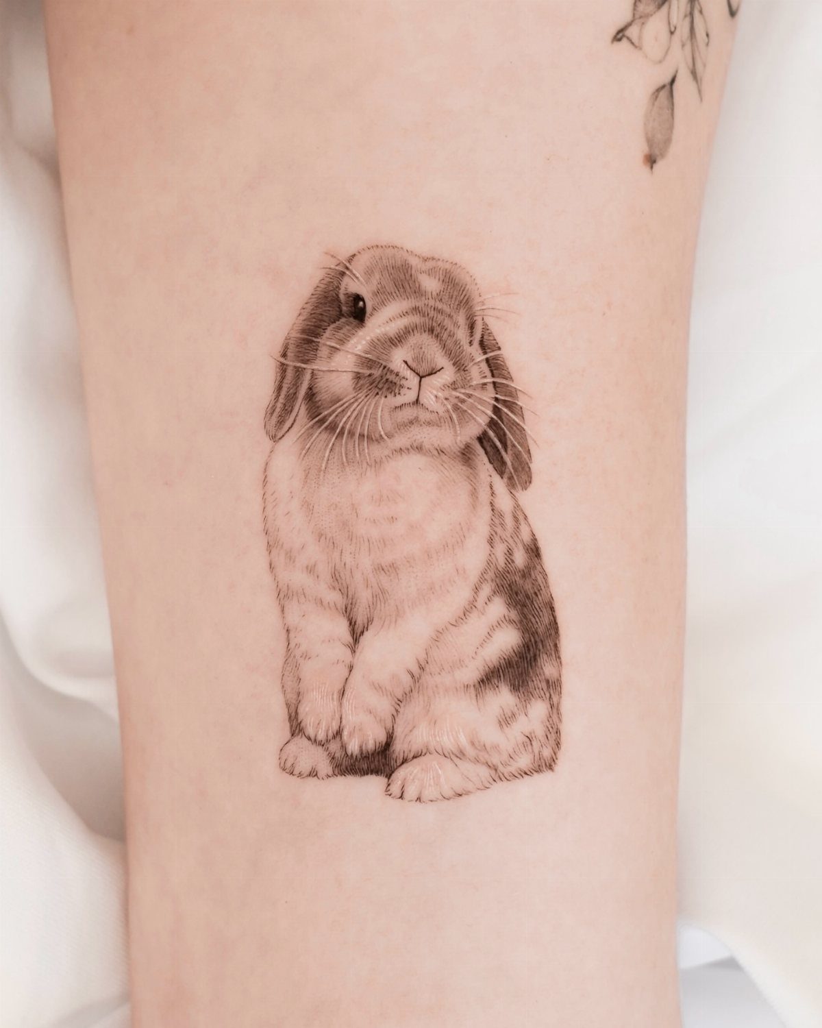 Small rabbit tattoo with detailed brown fur on a person's arm.
