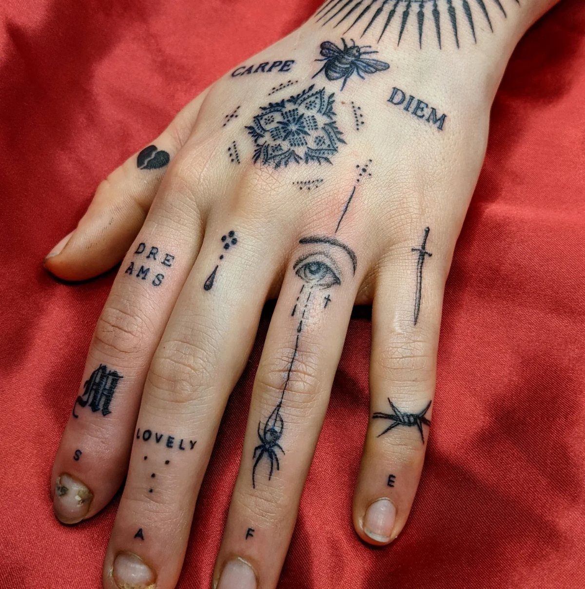 Tattooed hand with Carpe Diem and other small words and symbols on red fabric