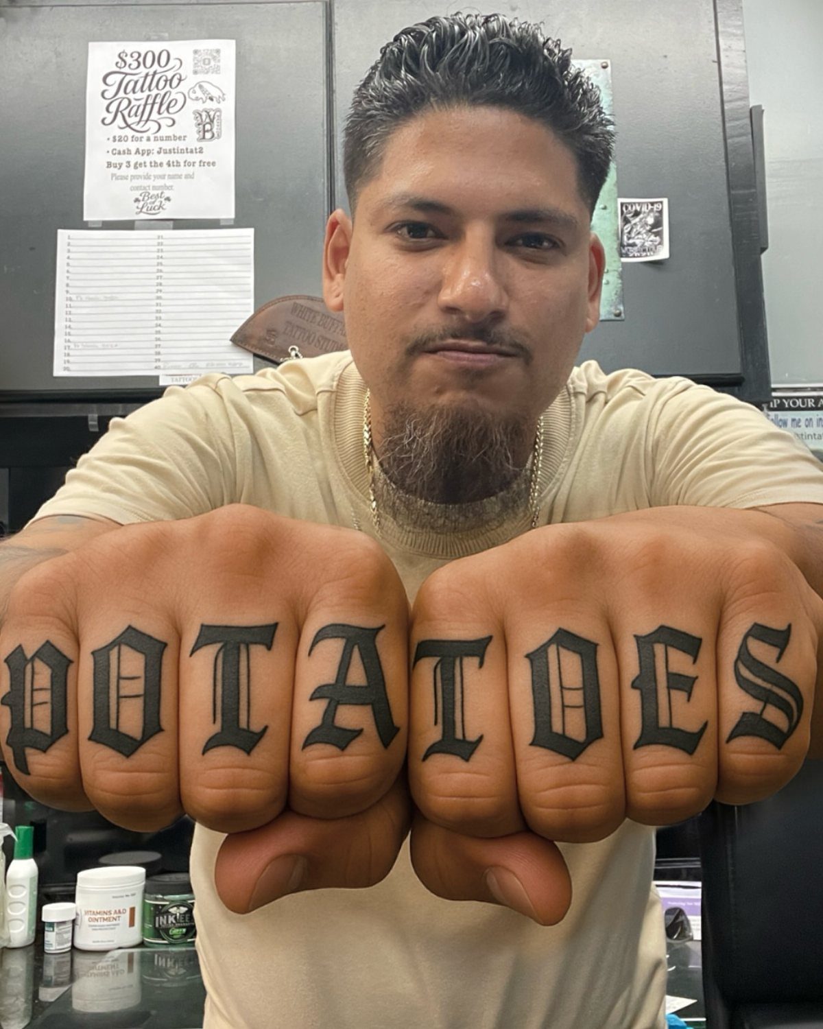 Man showing knuckle tattoos that spell out the word POTATOES in gothic font
