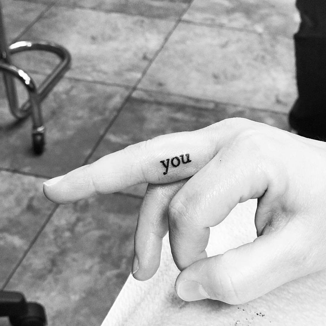 Hand with the word you tattooed on the side of the index finger