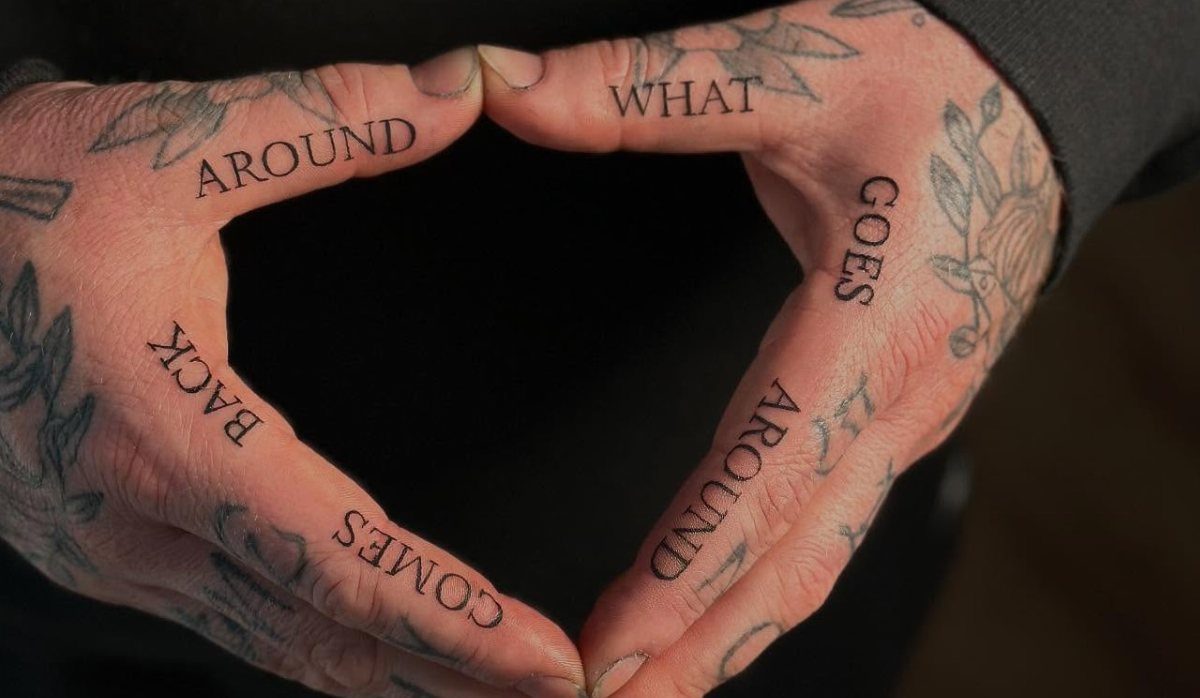 Hands forming a heart with what goes around comes around finger tattoos