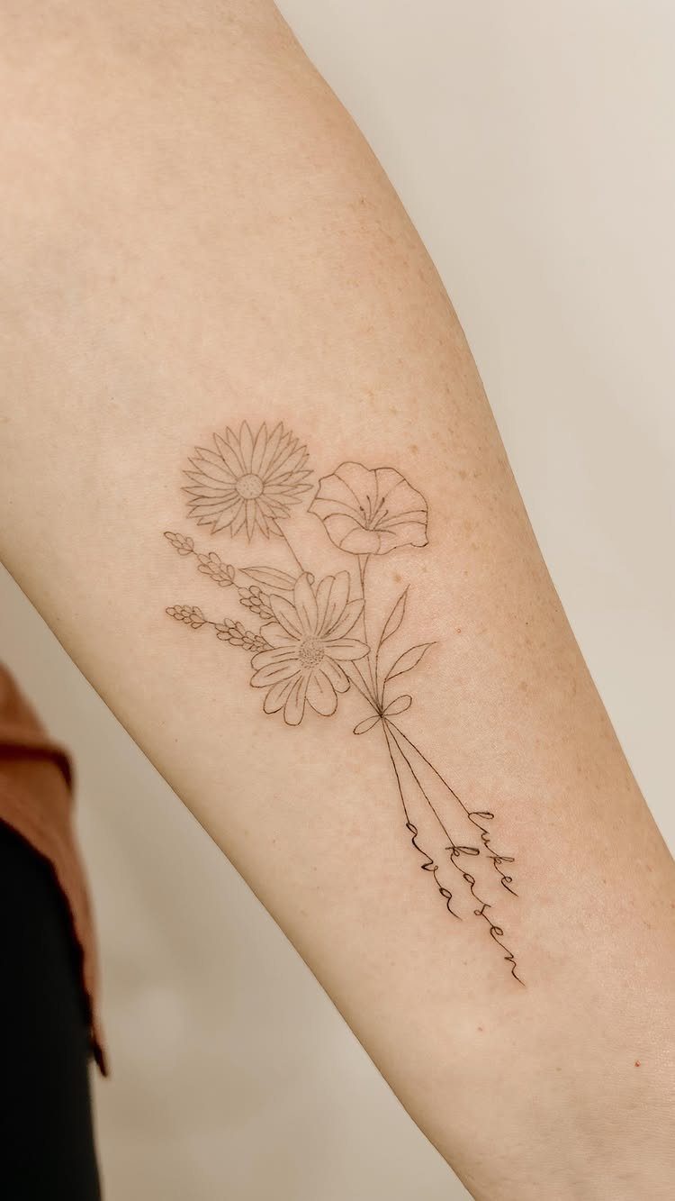 Floral bouquet tattoo on a forearm with names integrated into the stems.