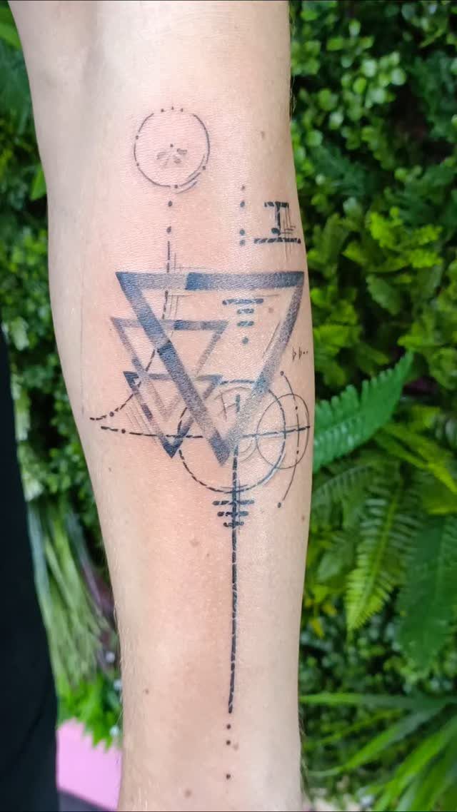 Abstract geometric tattoo on a forearm with triangles, circles, and fine lines.