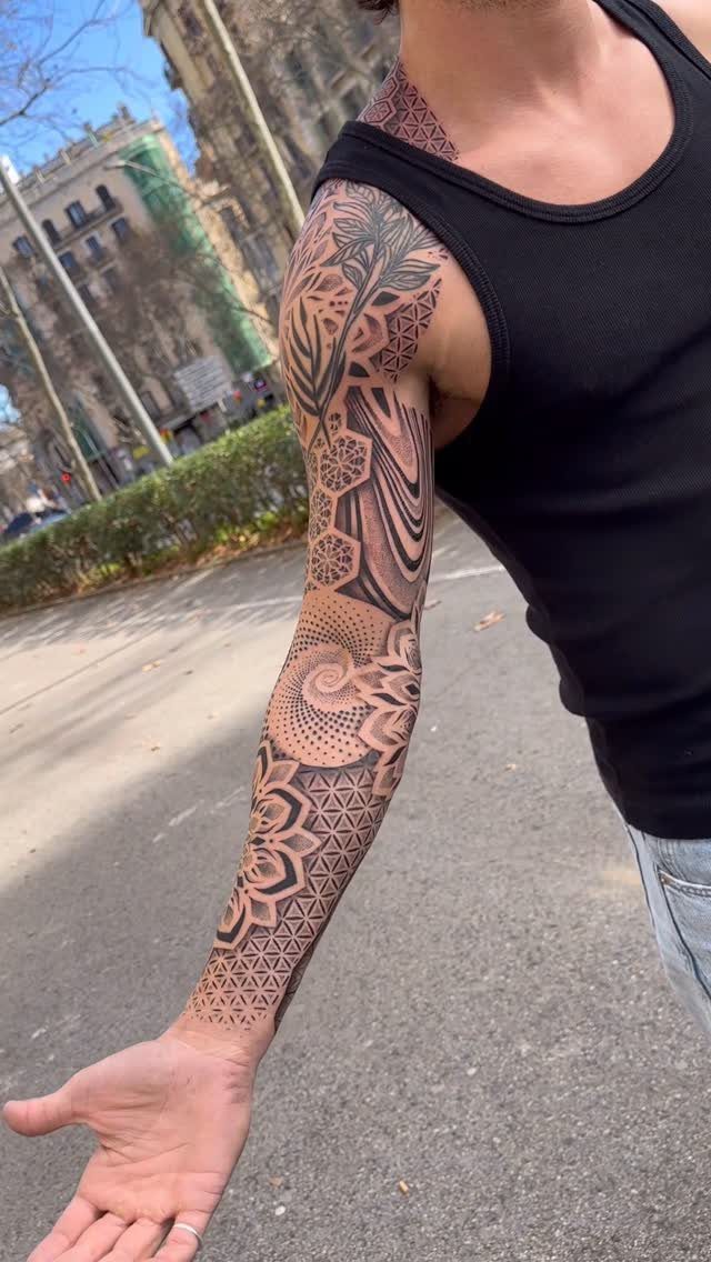 Detailed geometric tattoo sleeve on an arm featuring sacred geometry and mandala patterns.