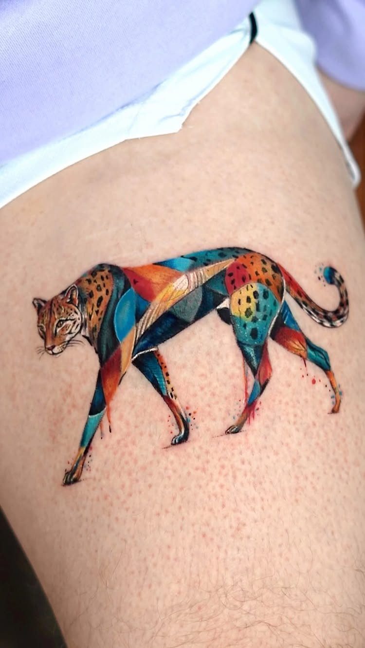 Colorful geometric leopard tattoo on a person's thigh with vibrant blue and orange tones.