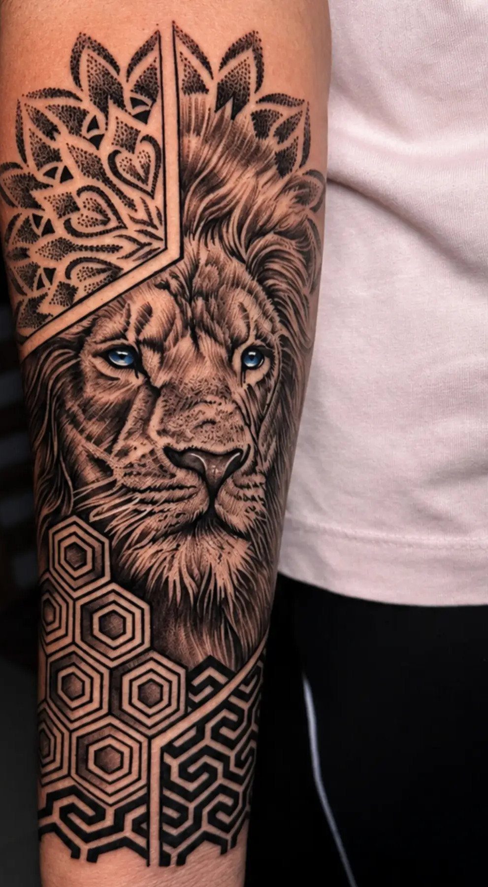 Lion head tattoo with realistic features and intricate geometric patterns on an arm.