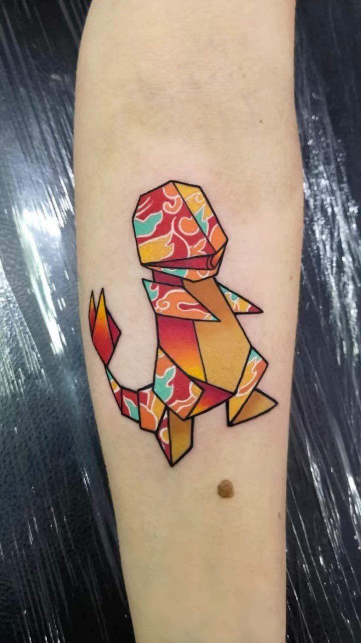 Geometric origami tattoo of a colorful creature on a person's forearm