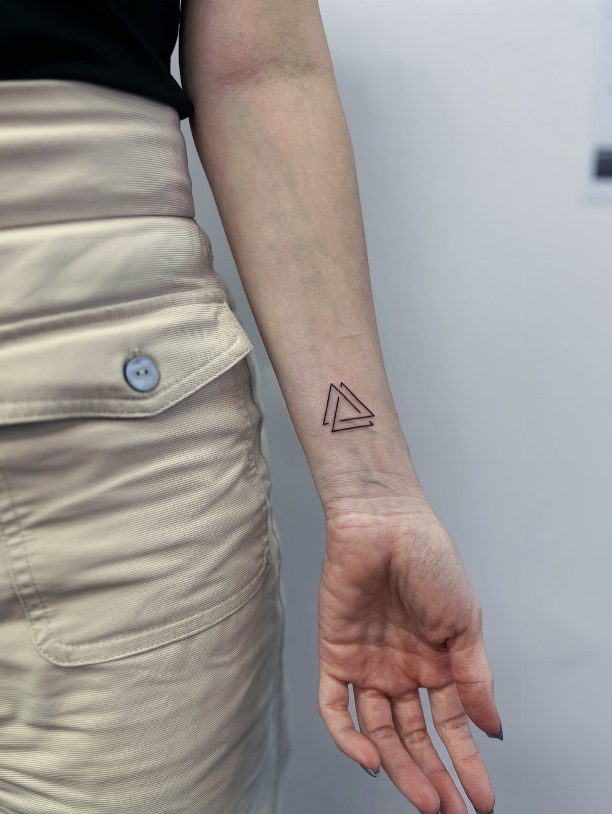 Interlocking triangle tattoo on a person's inner wrist against a white background
