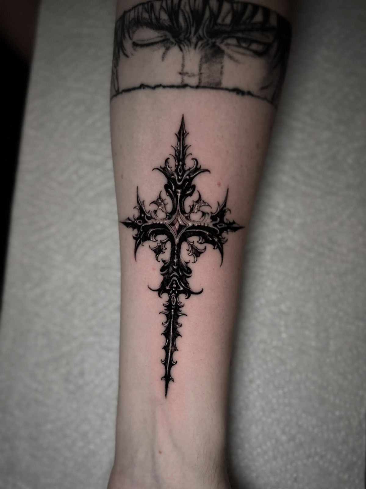 Symmetrical gothic cross tattoo with sharp thorns and spikes on a forearm