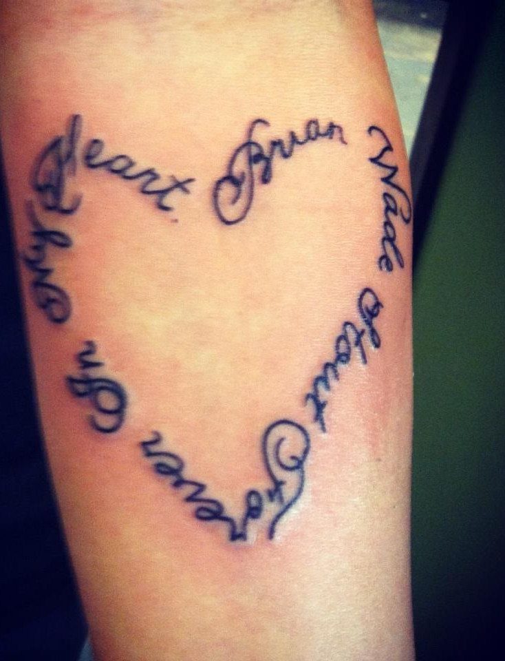 Cursive name tattoo forming a heart shape on a person's arm.
