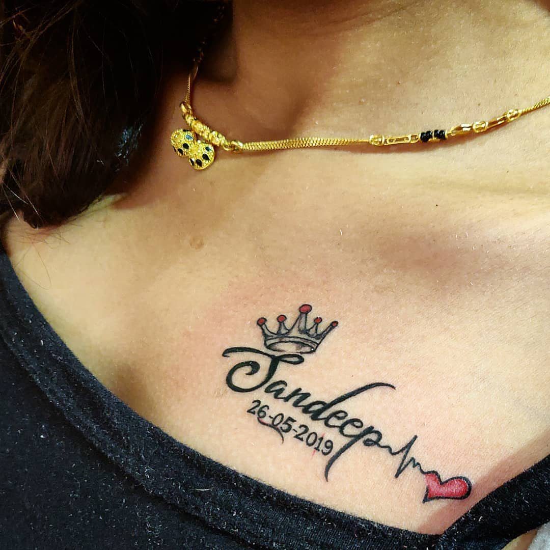 Tattoo of the name Sandeep with a heartbeat line and small red heart.
