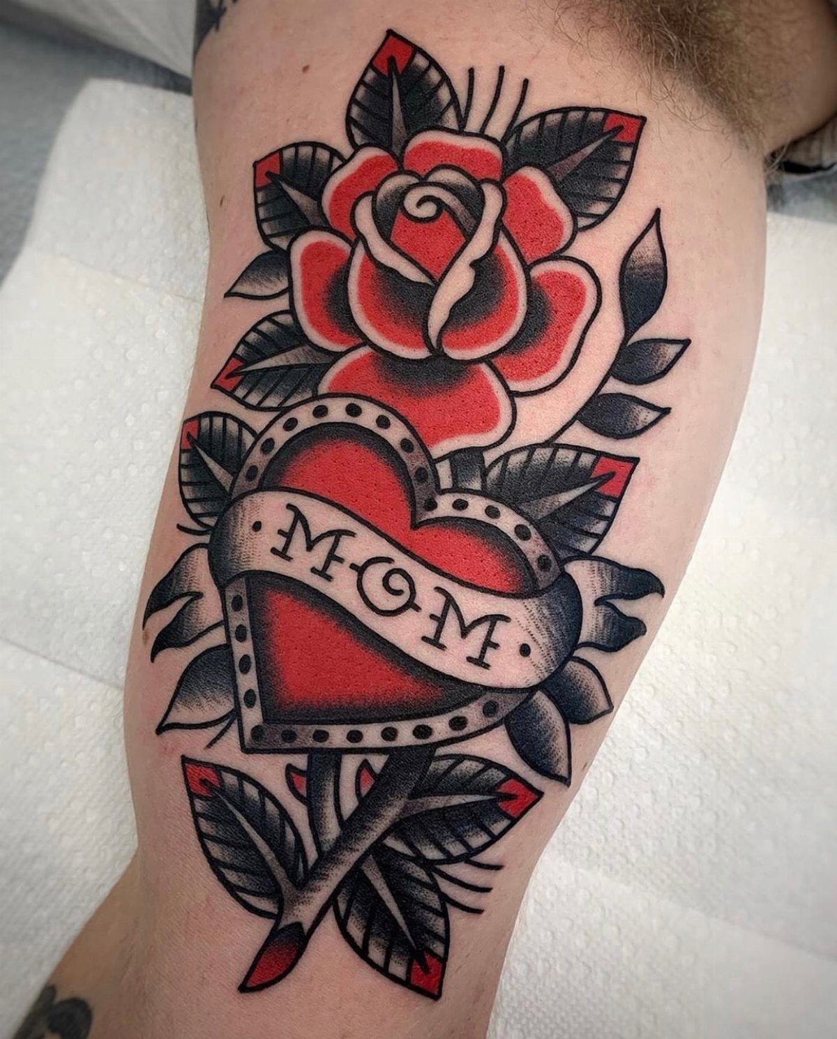 Traditional red heart tattoo with a Mom banner and a red rose