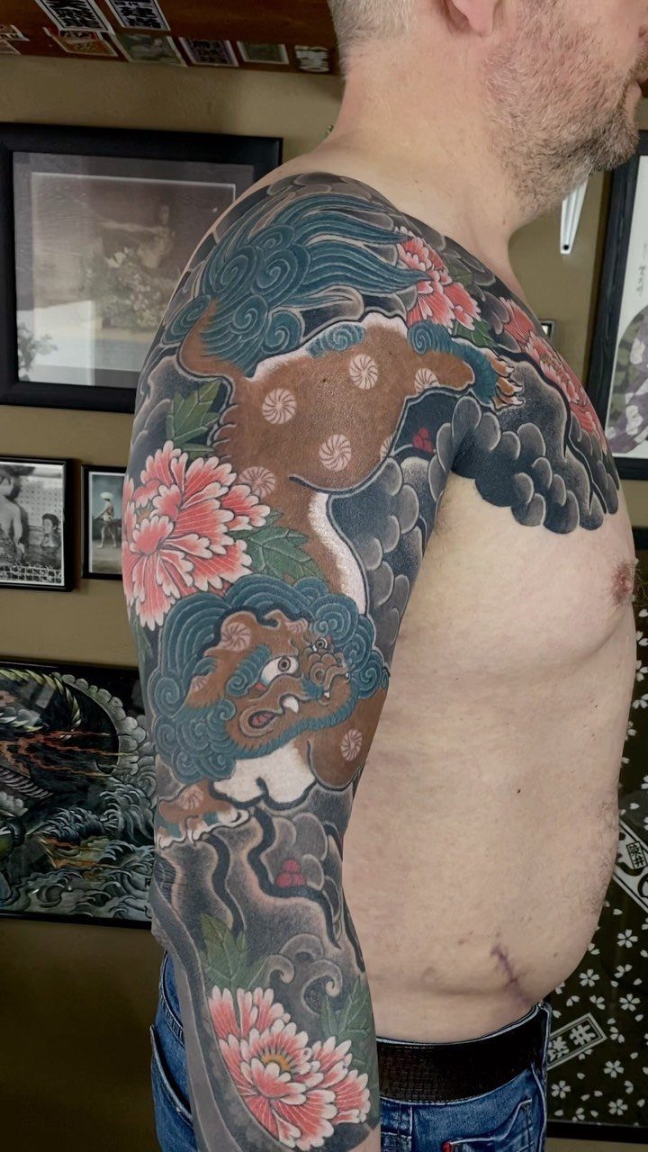 Japanese tattoo on a man's arm and chest with clouds and flowers