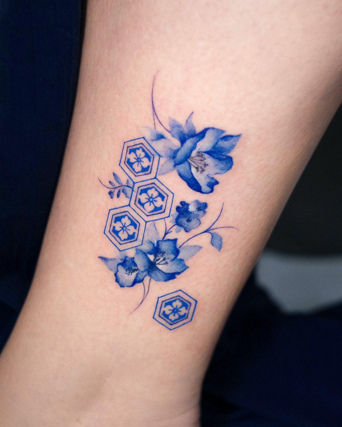 Blue floral tattoo with hexagonal patterns on a person's arm or leg.