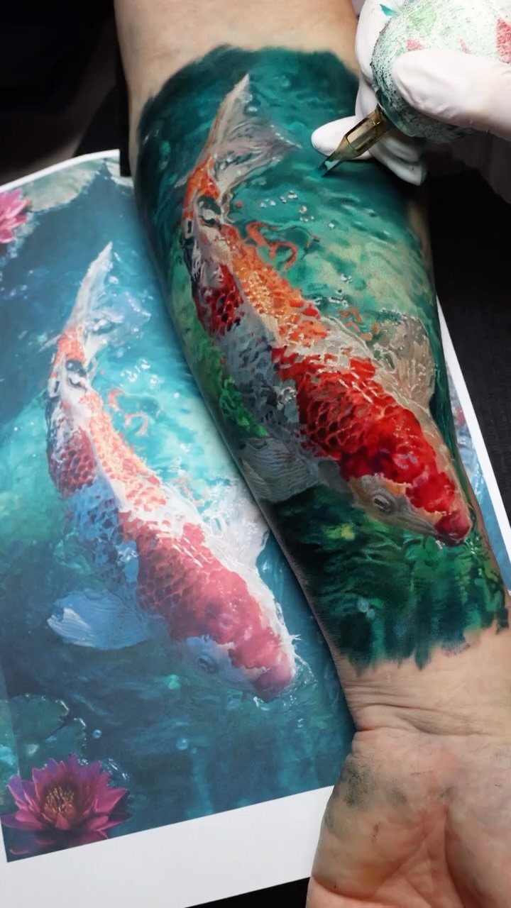 Koi fish tattoo on a forearm being worked on by a tattoo artist