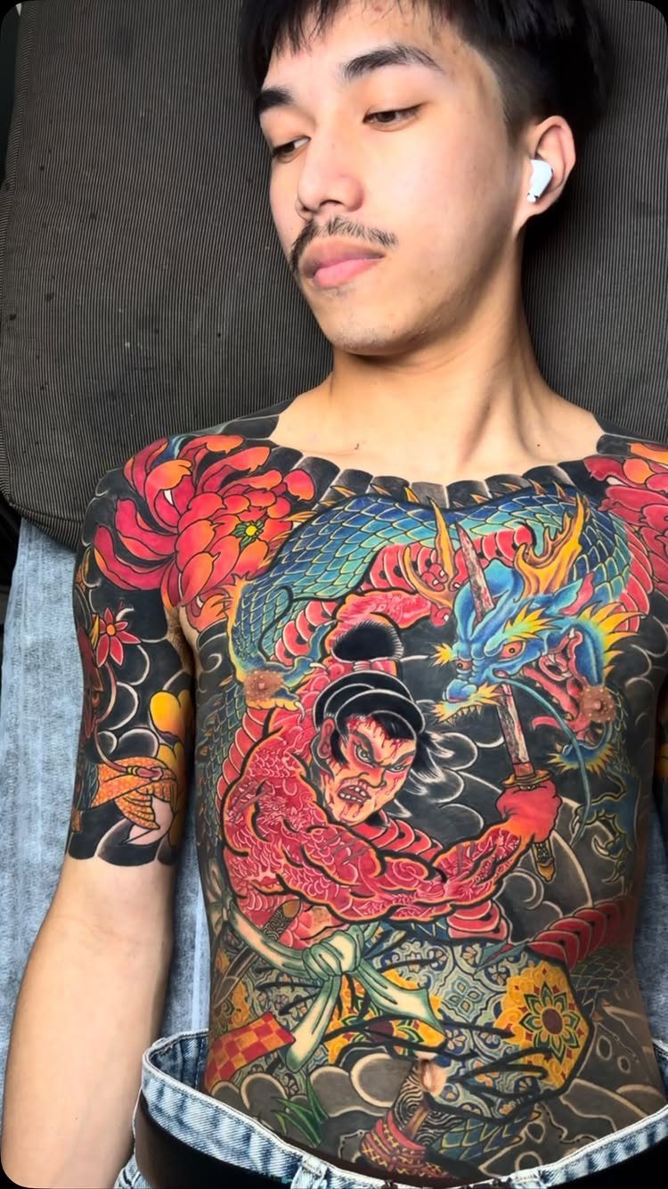 Man with a detailed Japanese tattoo featuring a dragon and warrior on his torso