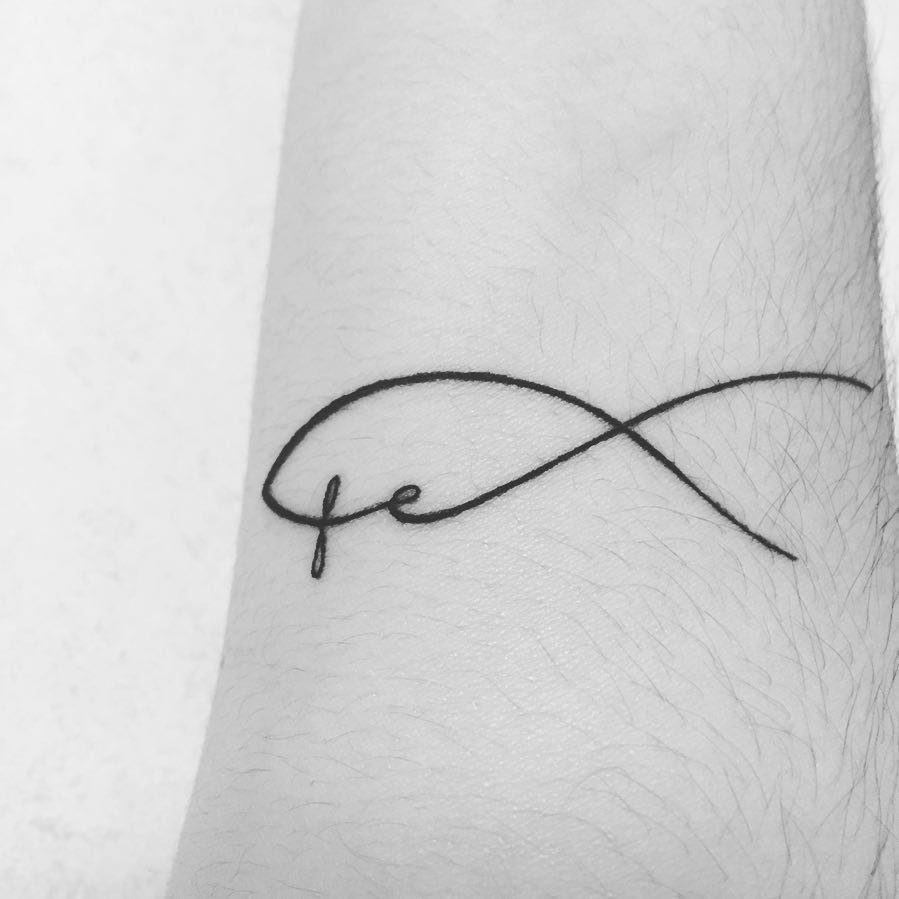 Black ink fish tattoo with cursive letters on a person's forearm