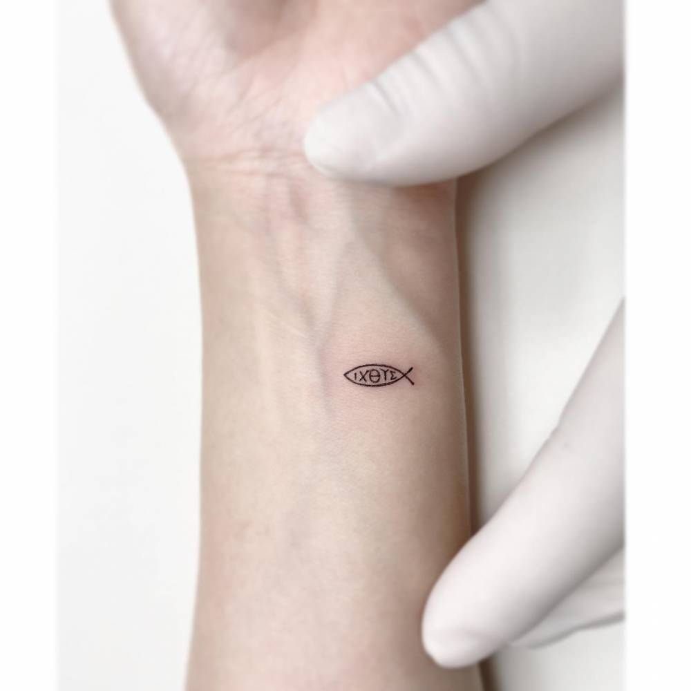 Small black ink fish tattoo with Greek letters on a person's inner wrist