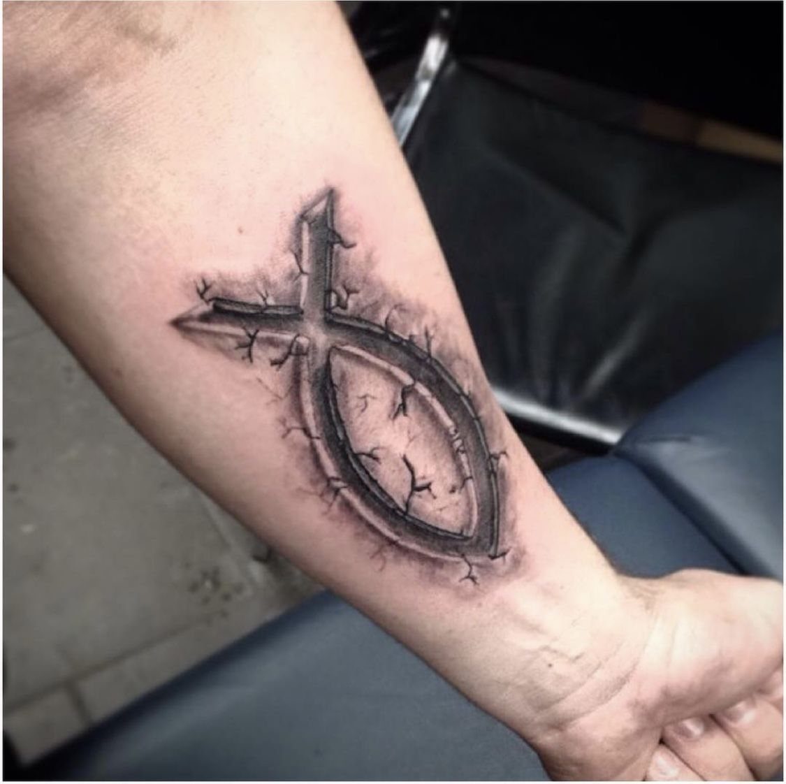 3D Jesus fish tattoo with an integrated cross on a person's forearm
