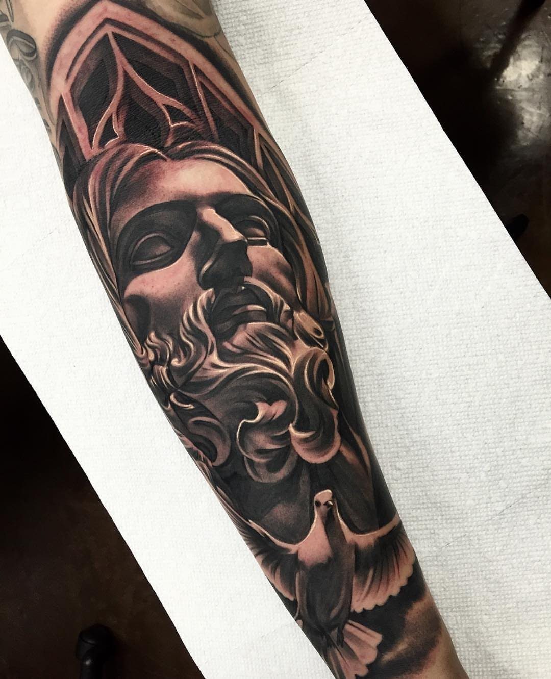 Jesus portrait tattoo with a flying dove on a person's forearm