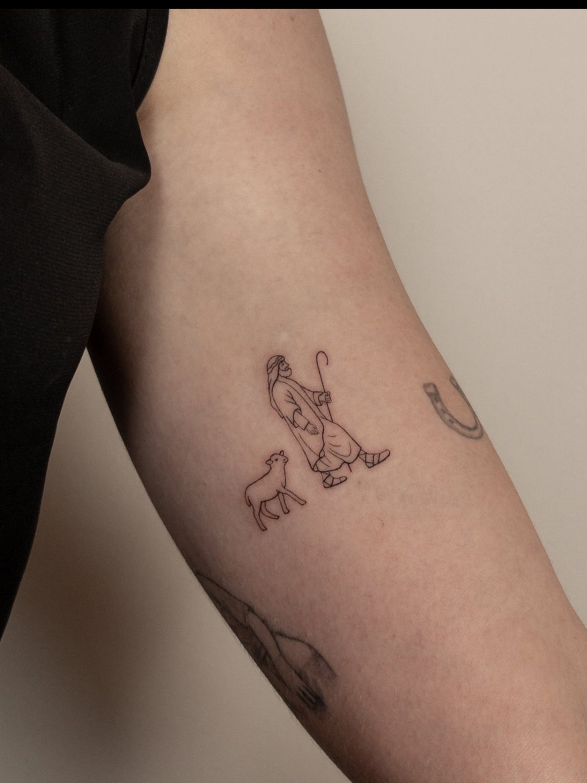 Line tattoo of Jesus as a shepherd with a lamb on an arm