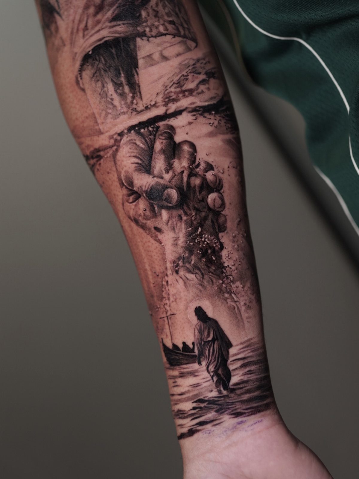 Black and grey forearm tattoo showing Jesus walking on water near a boat.