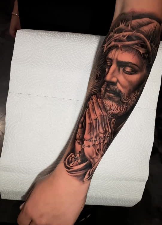 Jesus tattoo on forearm showing a praying portrait with a crown of thorns