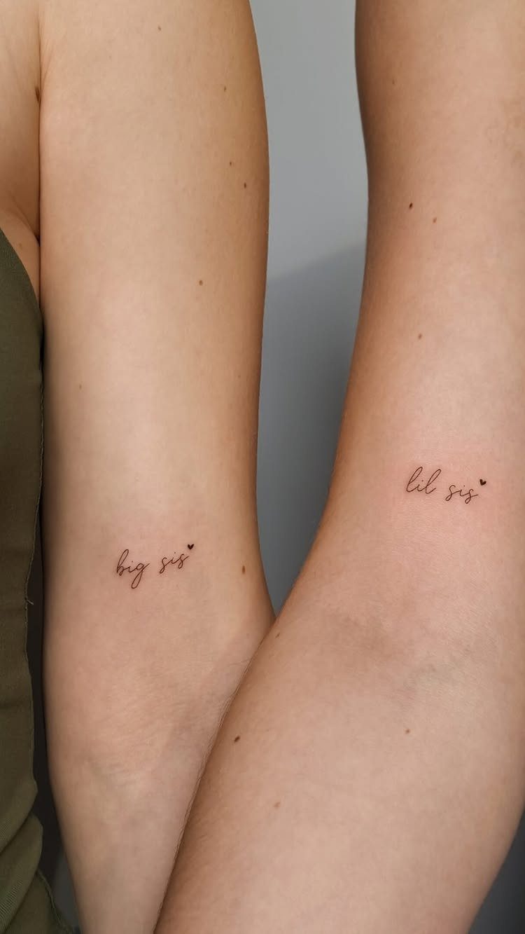Two forearms with matching cursive tattoos reading big sis and lil sis.