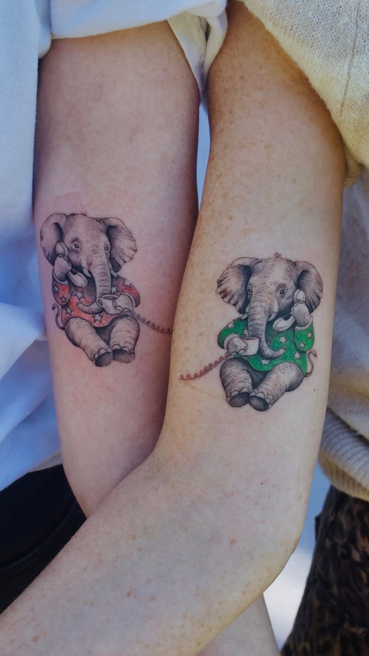 Matching elephant tattoos on two forearms, connected by a thin red line.