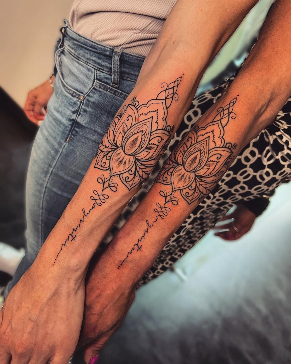 Matching floral mandala and always sister tattoos on two forearms side by side