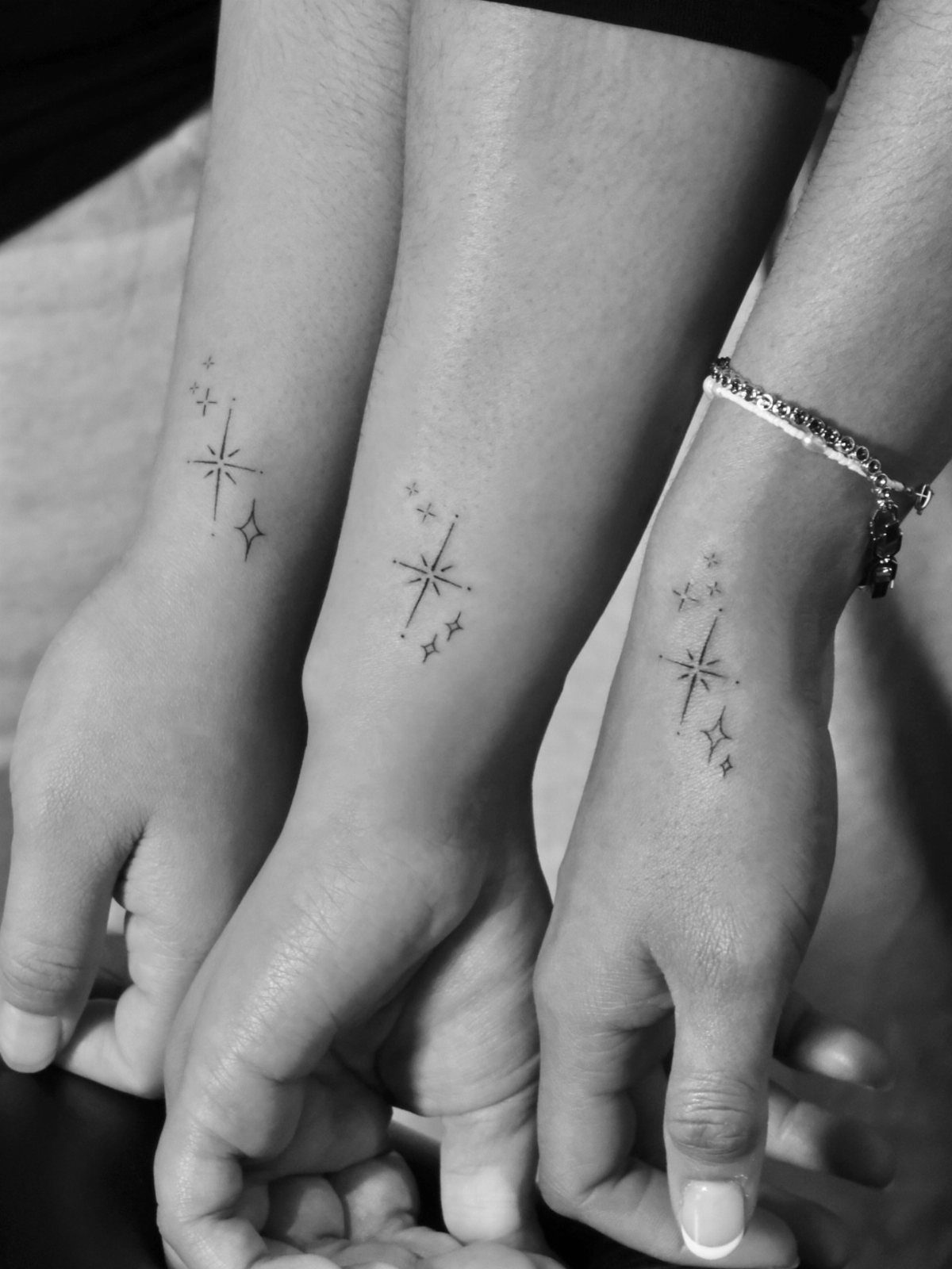 Three wrists with matching small star and dot tattoos on the inner wrist.