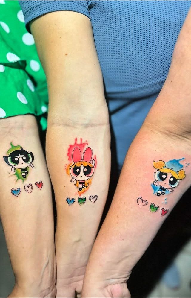 Three matching Powerpuff Girls tattoos on forearms with small colorful hearts below each.