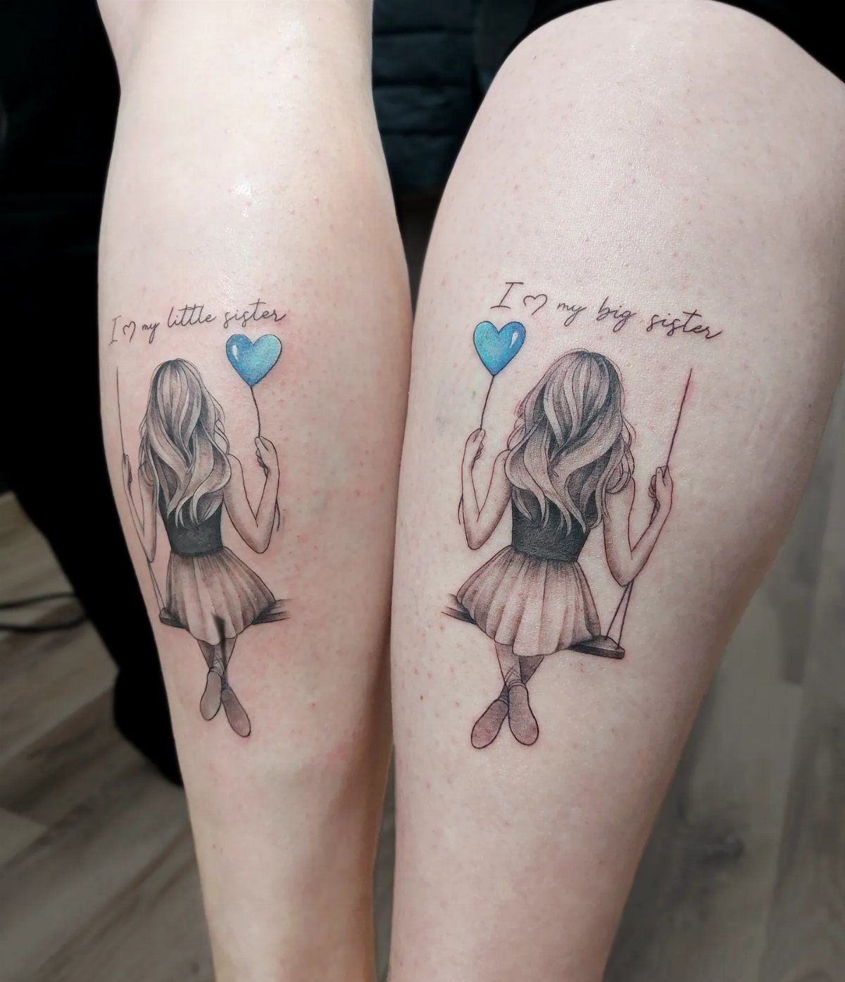 Matching sister tattoos of girls on swings with blue heart balloons on calves