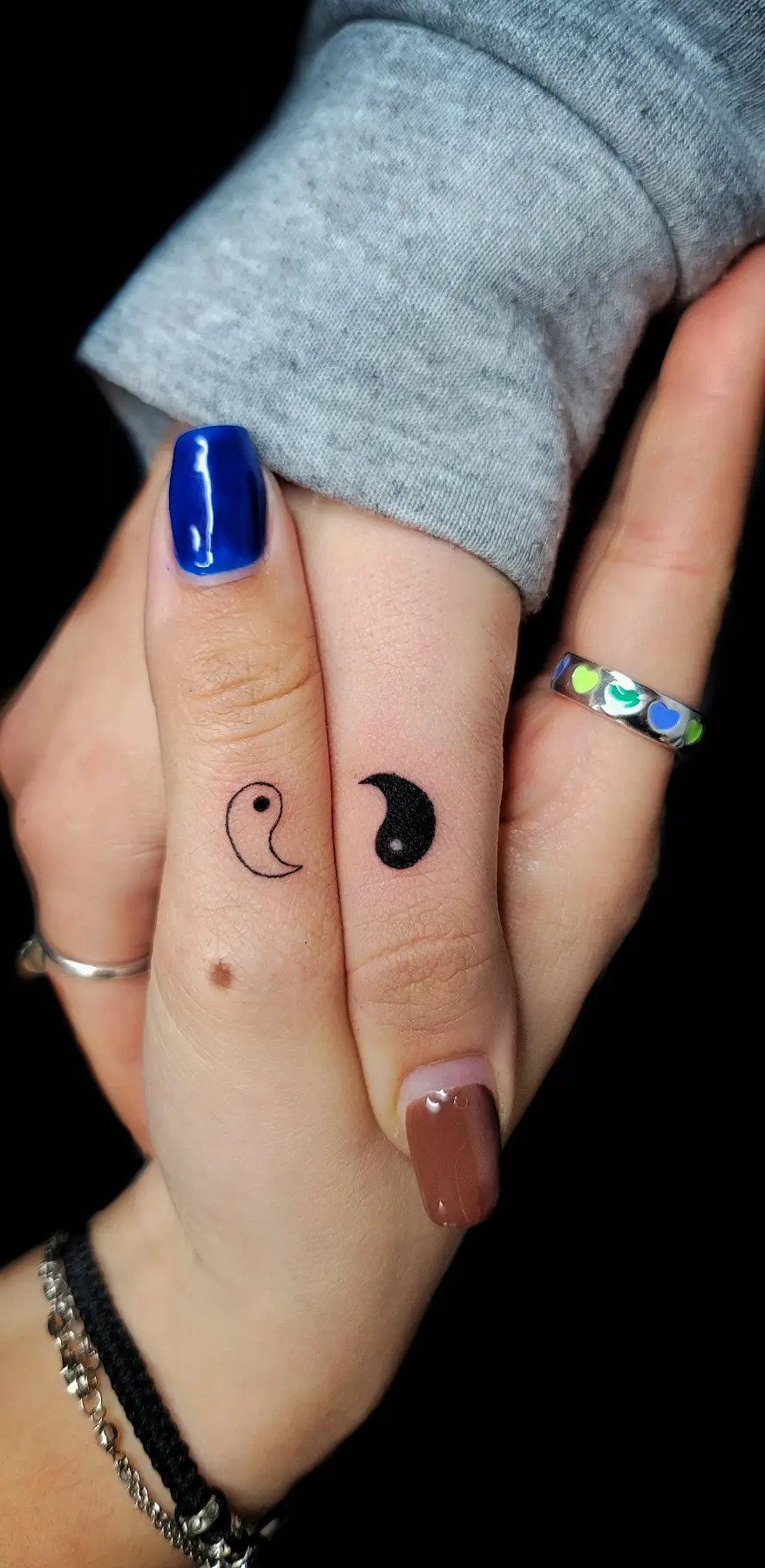 Two fingers touching with matching yin-yang symbol tattoos split between them.