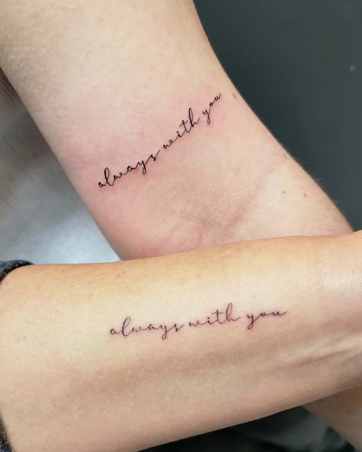Two forearms with matching cursive tattoos that read always with you