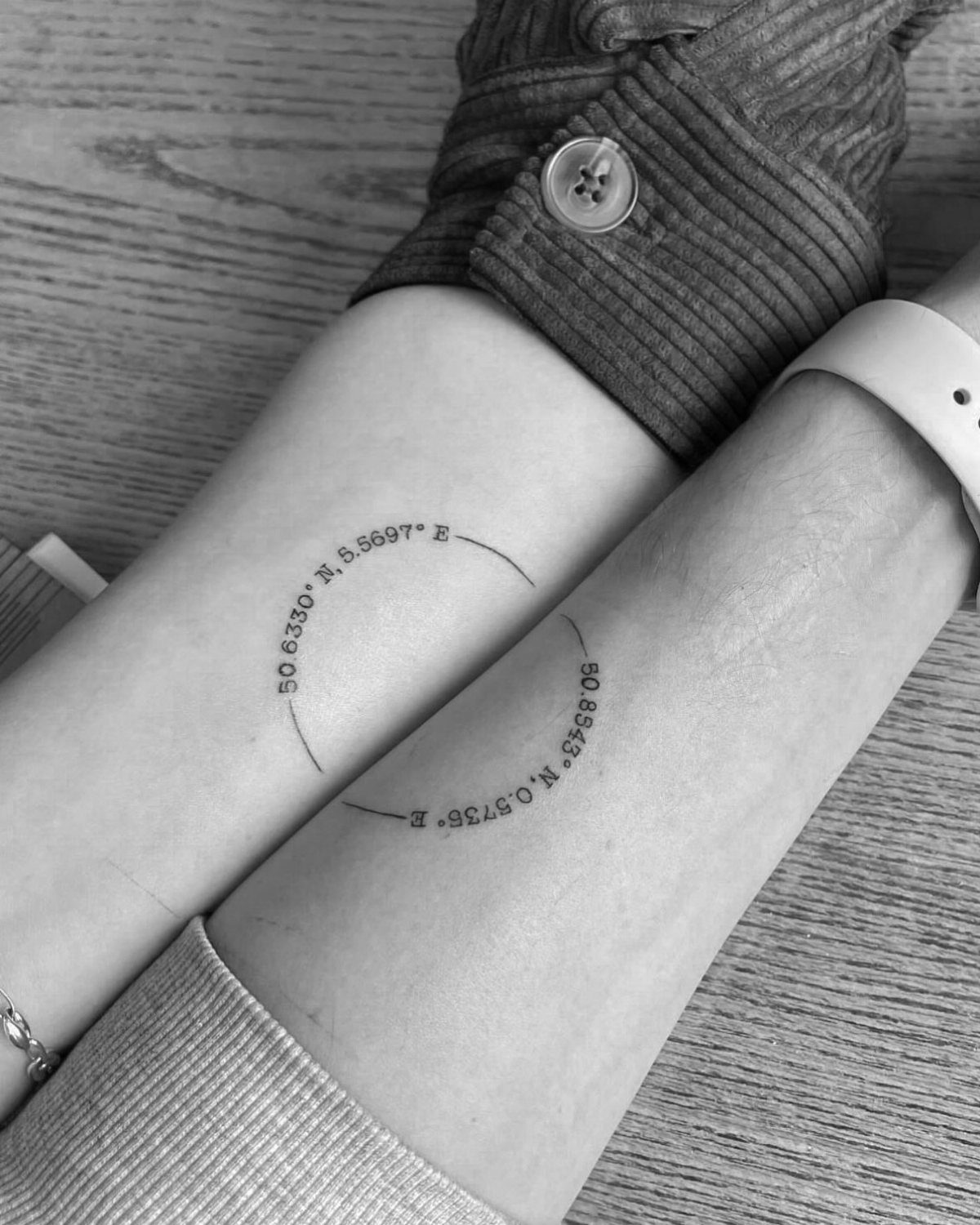 Two forearms with matching coordinate tattoos that form a circle when placed together.