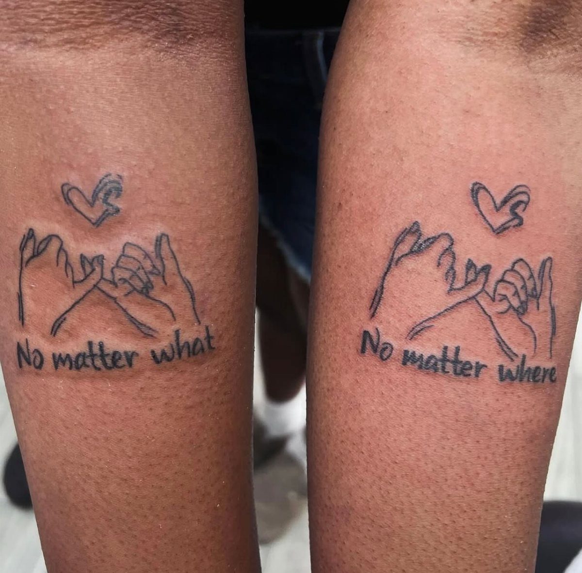 Matching pinky promise tattoos on two arms with complementary phrases and small hearts.