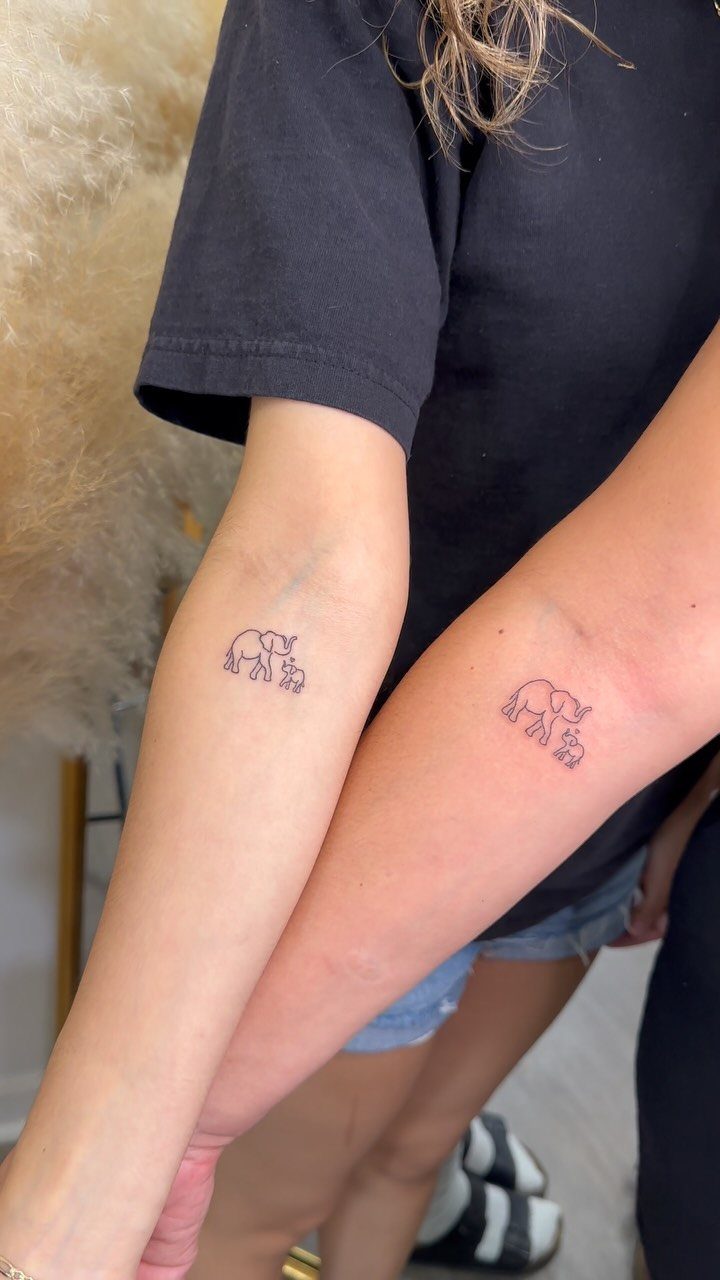 Two matching tiny elephant tattoos on the inner forearms of two people.
