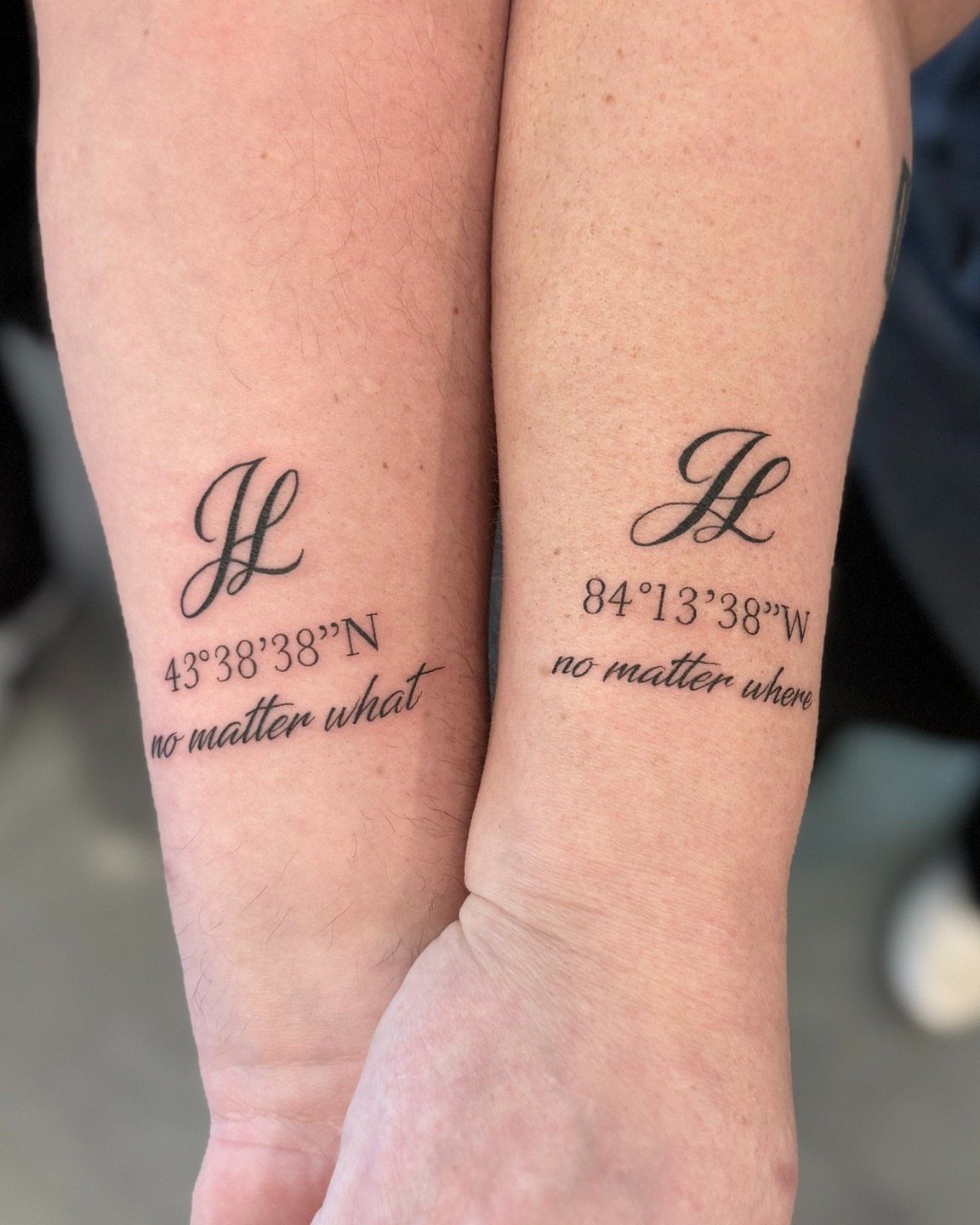 Matching wrist tattoos with cursive letters, geographical coordinates, and meaningful phrases.