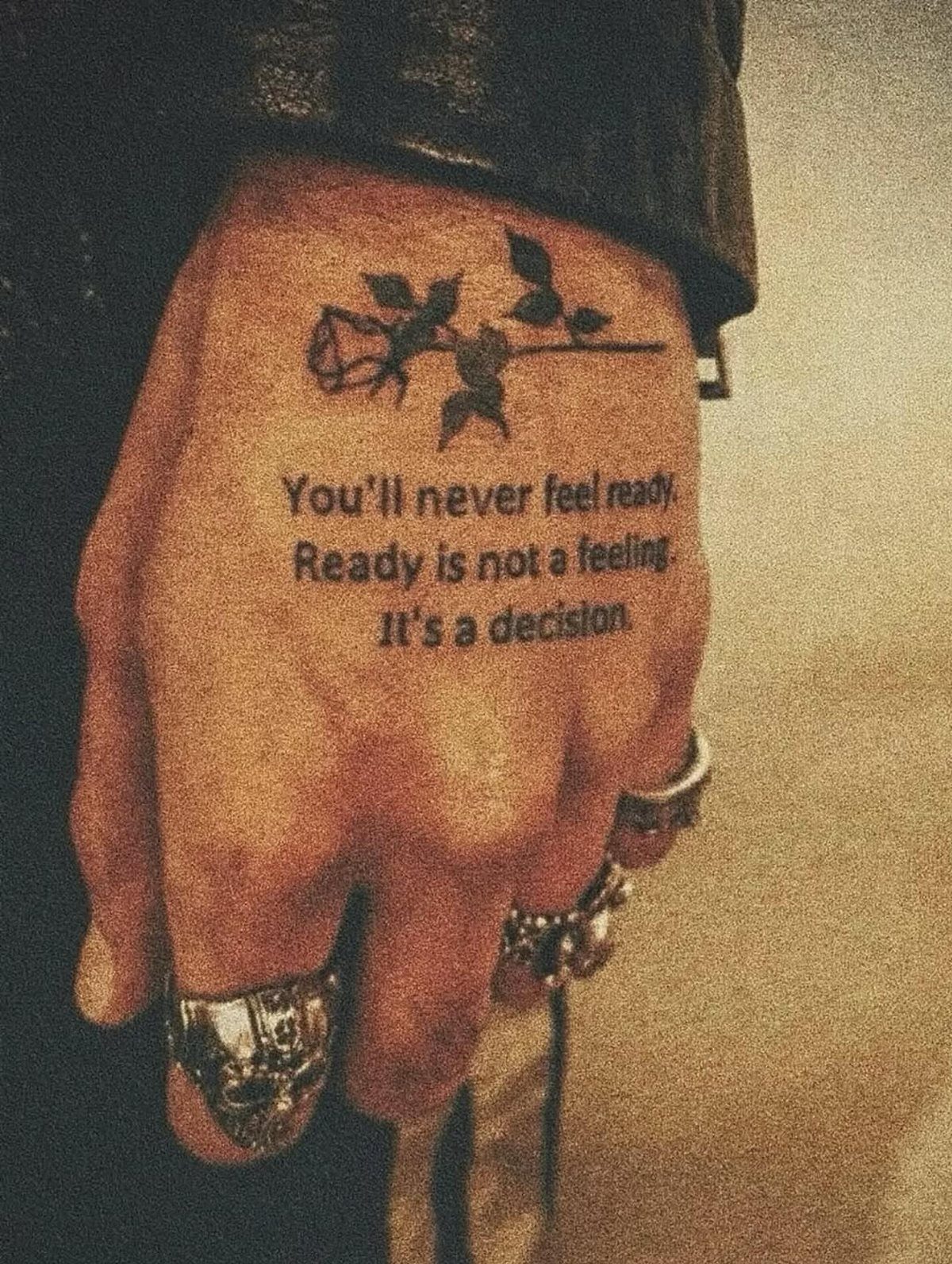 Hand with a rose tattoo and a motivational quote about making decisions.