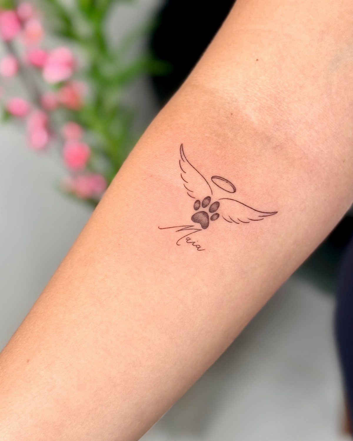 Dog paw tattoo with angel wings, a halo, and the name Mia.