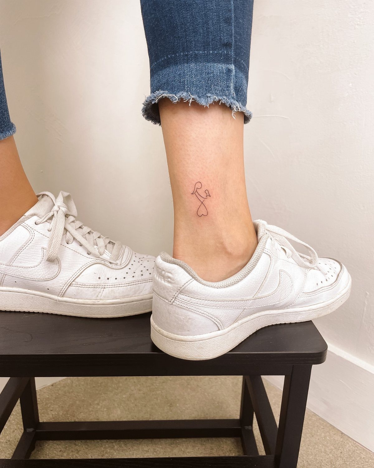 Small red single line heart and key tattoo on a person's ankle