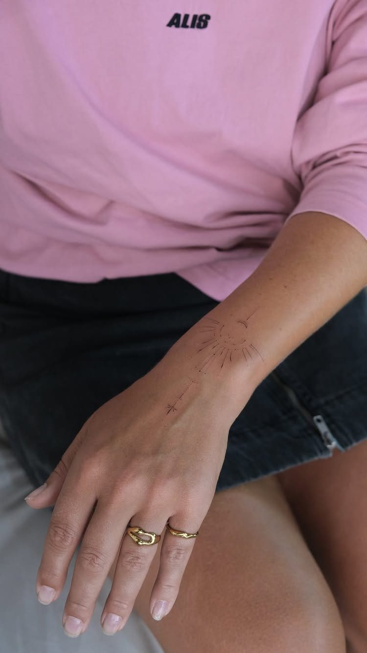 Small fine line sun tattoo on a person's inner wrist and forearm.