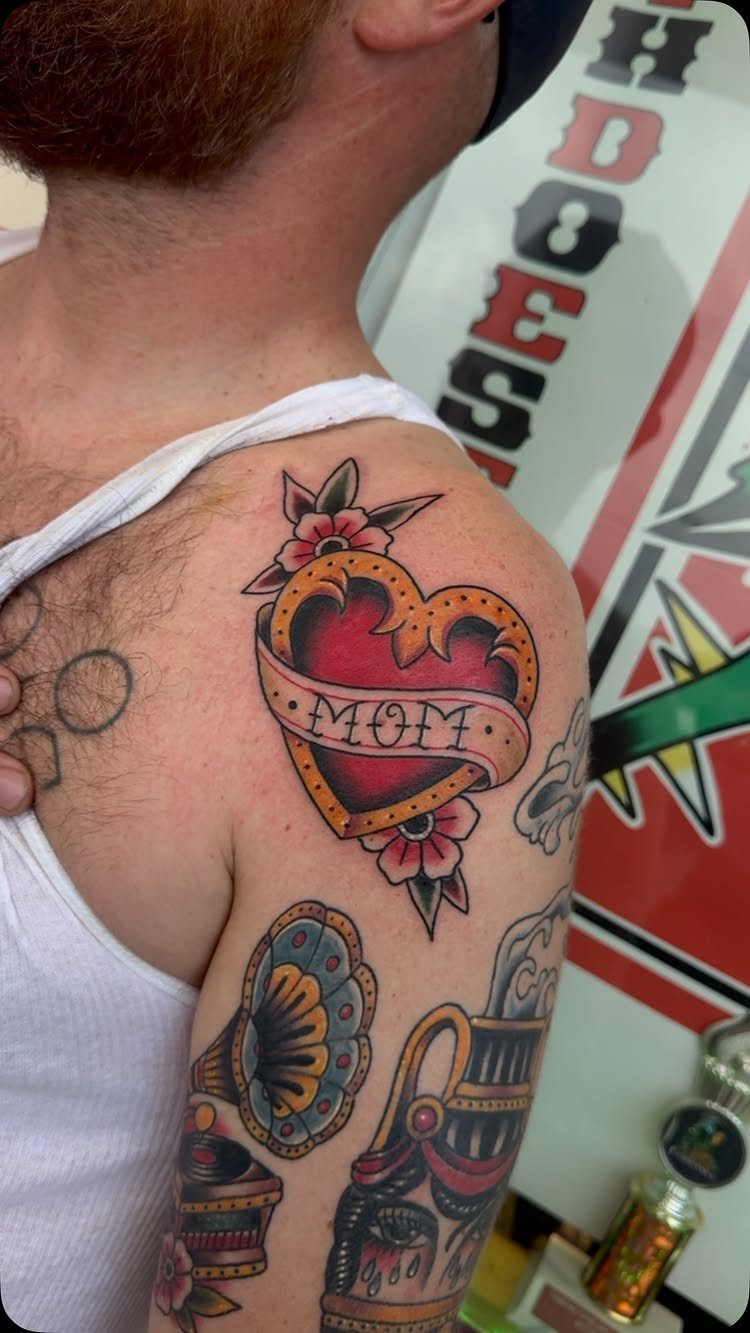 Traditional red heart tattoo with Mom banner on a person's shoulder