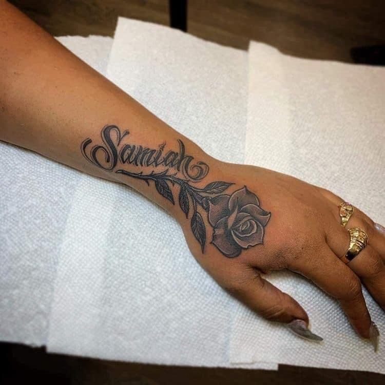 Cursive name tattoo reading Samiah with a rose and leaves on a hand