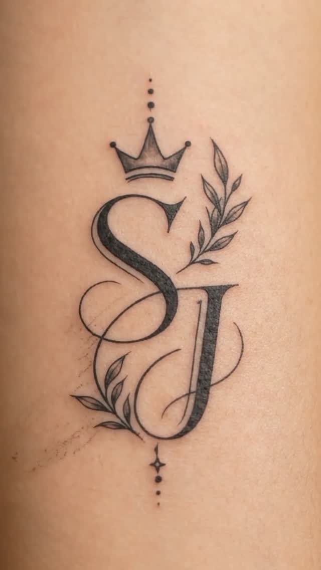 Stylized SJ name tattoo with a crown and botanical leaf accents on skin