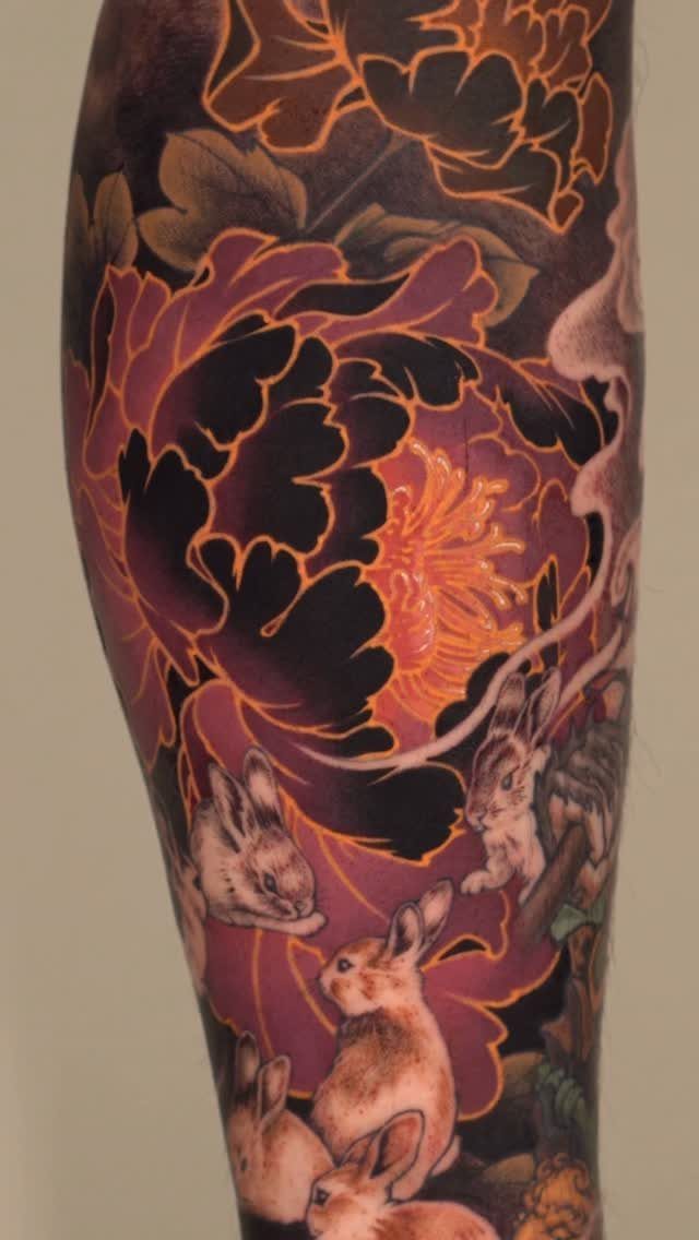 Neo traditional tattoo on a leg featuring red peonies and small brown rabbits