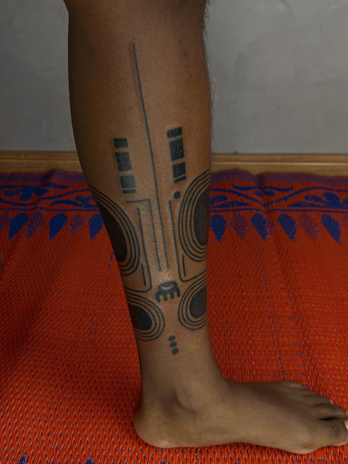 Neo-tribal tattoo with black geometric lines and curves on a person's lower leg.