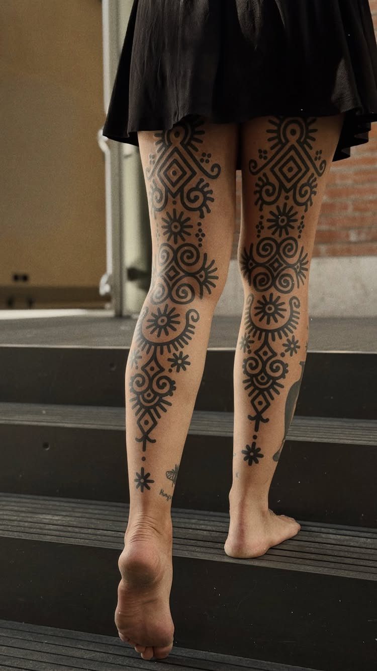Legs with bold black neo-tribal tattoos standing on dark grey outdoor stairs
